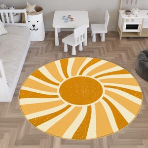 May include: A round area rug featuring a central orange circle surrounded by radiating curved stripes in alternating shades of light cream and mustard yellow, with a subtle distressed texture throughout the entire pattern.