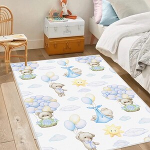 Può includere: Tappeto rettangolare bianco con un motivo ripetuto di orsacchiotti, palloncini, nuvole e soli. Gli orsi tengono in mano palloncini e fluttuano. Alcuni orsi sono in cesti con fiori blu. La tavolozza dei colori include blu, giallo e beige.