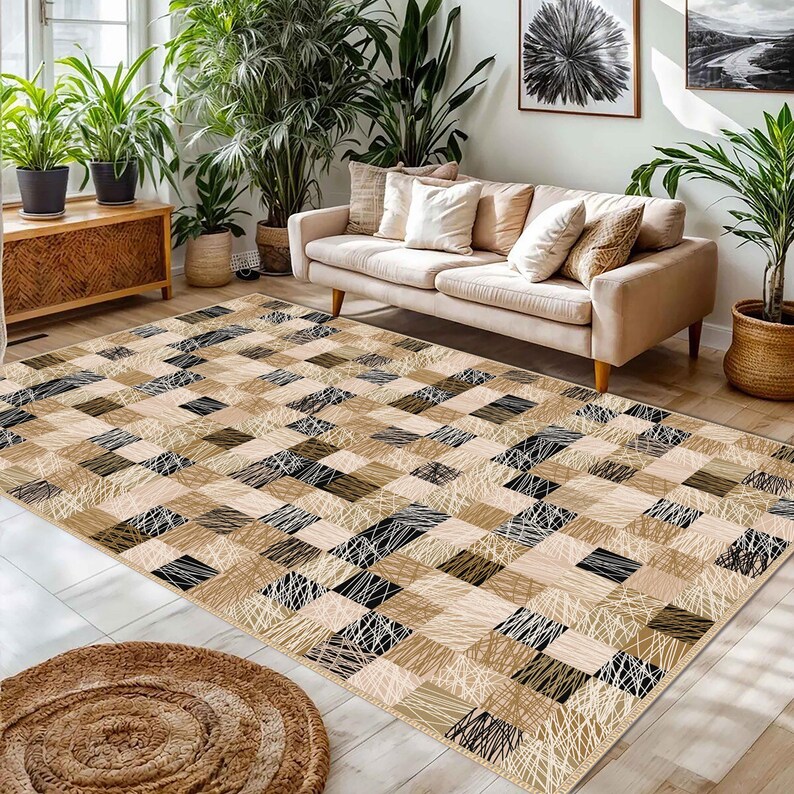 May include: A rectangular rug with a patchwork design in beige, brown, and black. The rug features solid squares and squares with linear patterns. A round, woven rug is in the foreground. The rug is suitable for a living room.