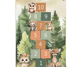 May include: A rectangular blanket featuring a hopscotch game design with numbers one through ten in orange and green squares. The background displays a watercolor forest scene with illustrations of an owl, raccoon, rabbit, and deer wearing flowers.