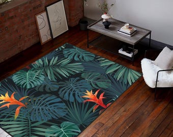 May include: A rectangular area rug featuring a dark background with a dense pattern of large green monstera leaves, palm fronds, and vibrant orange bromeliad flowers. The botanical design covers the entire surface of the floor covering.