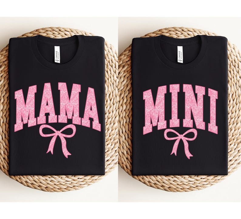 May include: Two black t-shirts with pink glitter lettering. One shirt says "MAMA" with a pink bow and the other says "MINI" with a pink bow.