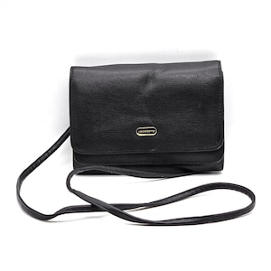 May include: Black leather crossbody bag with a gold-toned logo. The bag has a flap closure and a long adjustable strap.