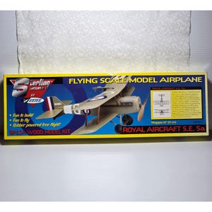 May include: A model airplane kit of a Royal Aircraft S.E. 5a biplane. The box is yellow and blue, with the plane's image and text that reads "Flying Scale Model Airplane." The wingspan is 24 inches.