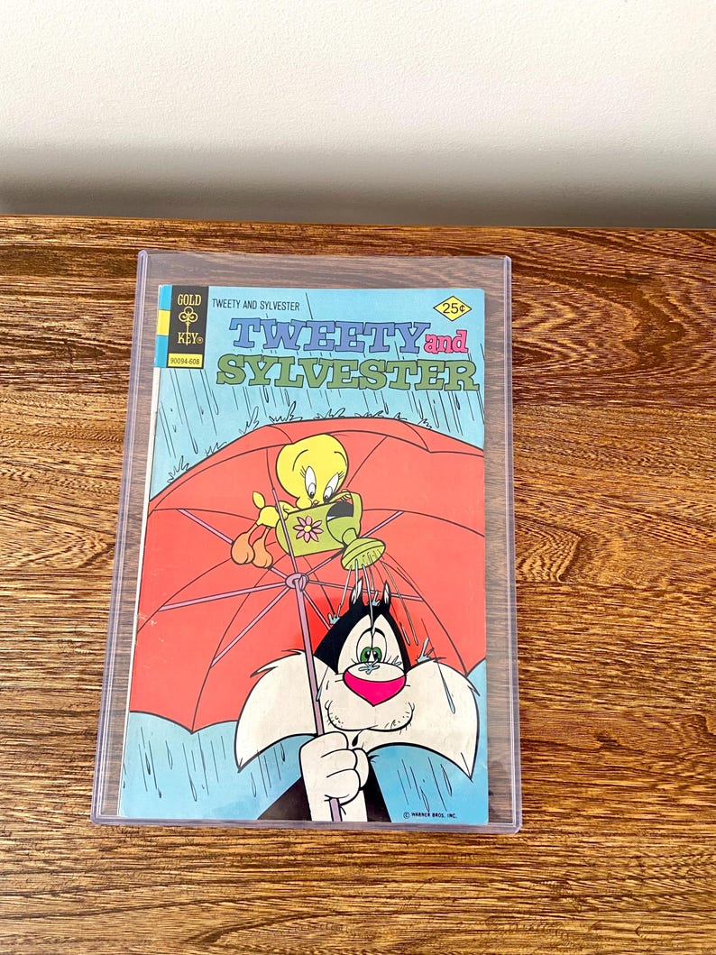 May include: A vintage comic book cover featuring Tweety Bird and Sylvester the Cat. The cover is blue with a red umbrella and a yellow bird holding a watering can. The title of the comic is "Tweety and Sylvester" and the price is 25 pence.