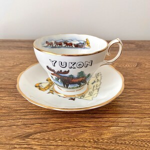 Queen Anne Souvenir Teetasse mit Untertasse, Yukon, Kanadisches Territory, Elch, Hundeschlitten, Mountie und Wildtiere, Landkarte Yukon, Fine Bone China, England