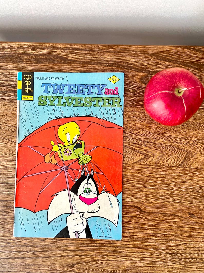 May include: A vintage comic book cover featuring Tweety Bird and Sylvester the Cat. The cover is blue with a red umbrella and rain. The title is "Tweety and Sylvester" with the price "25c" in a diamond shape. The comic book is from "Gold Key" comics.