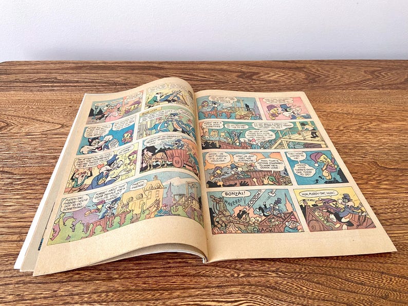 May include: A vintage comic book featuring a cartoon character with a red hat and a blue shirt. The comic book is open to a page with a panel showing the character riding a horse. The comic book is in good condition with some wear and tear.