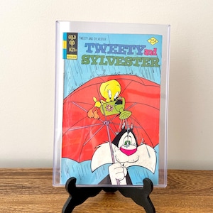 May include: A vintage comic book featuring Tweety Bird and Sylvester the Cat. The cover shows Tweety Bird holding a watering can and Sylvester the Cat holding a red umbrella. The comic book is titled "Tweety and Sylvester" and has a price of 25 pence.