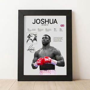 Op de afbeelding: Een ingelijste poster met een zwart-witportret van Anthony Joshua met rode bokshandschoenen aan. De print bevat zijn naam, carrièrestatistieken, een kleine actiefoto, een handtekening en een citaat, alles tegen een lichtgrijze achtergrond.