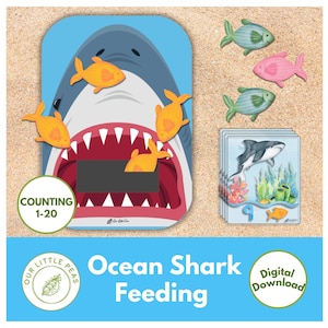May include: A blue and white shark with an open mouth and red teeth. The shark is surrounded by yellow fish. The image also includes a set of cards with a shark and numbers 1-20. The text "Counting 1-20" and "Ocean Shark Feeding" is also included in the image.
