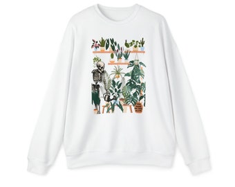 May include: White sweatshirt with a graphic print of a skeleton watering plants on a shelf. The text "You make me feel alive" is printed on the graphic.