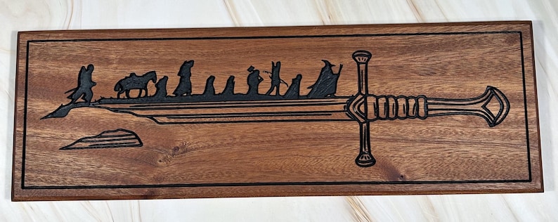 May include: A wooden sign with a black silhouette of a sword and a group of figures walking towards it. The sword is the iconic sword from the Lord of the Rings, and the figures are the hobbits from the story.