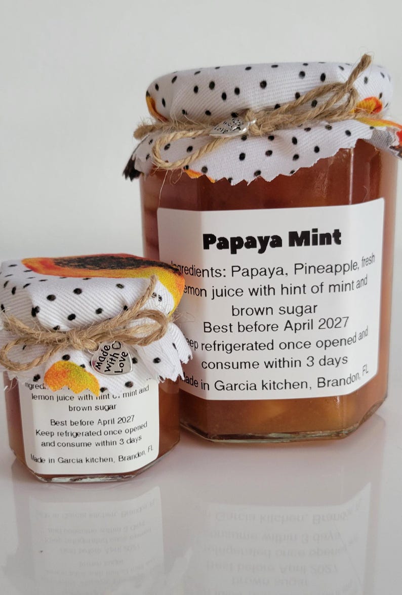 May include: Two jars of Papaya Mint jam with fabric-covered lids and twine ties. Labels detail ingredients and a 'best before' date. The smaller jar has a 'Made with Love' tag. The jars are filled with a brown preserve.