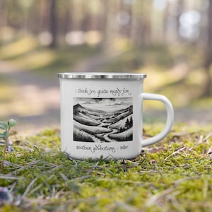 May include: White enamel mug with a silver rim and handle. The mug features a black and white landscape illustration with the quote, "I think I'm quite ready for another adventure. - Bilbo."