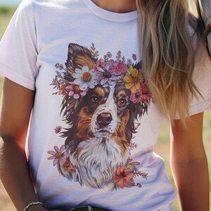 Könnte beinhalten: Eine Frau trägt ein weißes T-Shirt mit einem floralen Druck eines Hundekopfes. Der Hund trägt eine Blumenkrone. Die Frau steht neben einem weißen Pferd.
