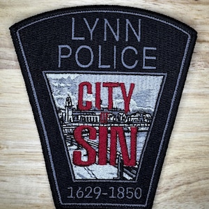 May include: Black and gray embroidered patch with the text "Lynn Police" and "City of Sin" in red and white. The patch also includes the dates "1629-1850".