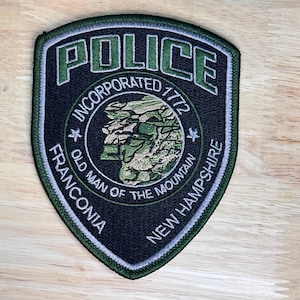 May include: Green and black embroidered patch with the words "Police", "Franconia", "Old Man of the Mountain", "New Hampshire", and "Incorporated 1772".