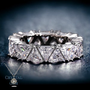 May include: A silver band ring with a row of triangular-shaped clear stones.