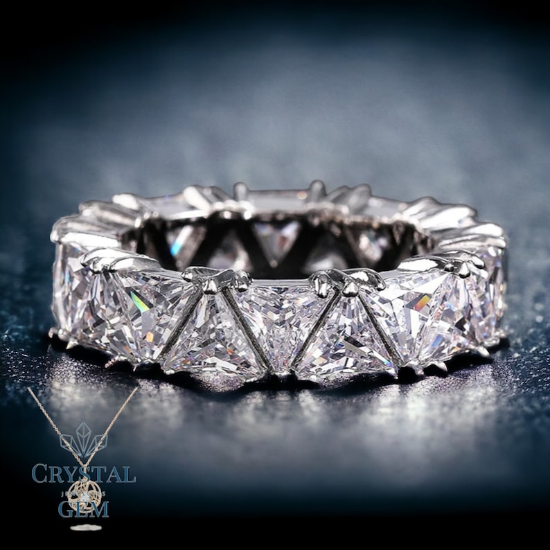 May include: A silver band ring with a row of triangular-shaped clear stones.