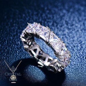 May include: A silver ring with a row of triangular-shaped clear stones set in a continuous band.