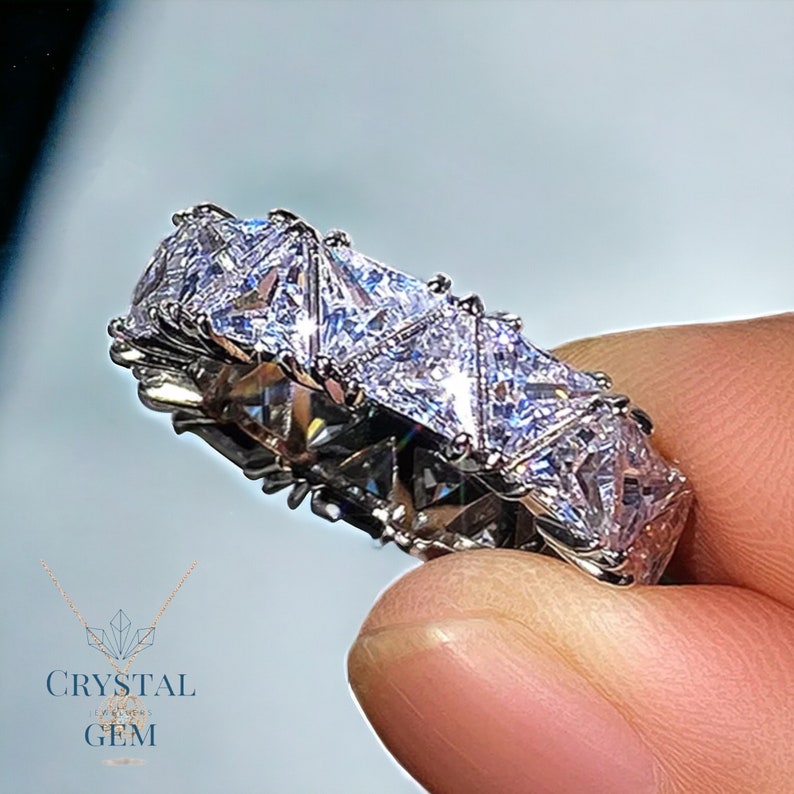 May include: A silver band ring with a row of triangular-shaped clear cubic zirconia stones.