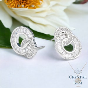 May include: A pair of silver earrings with a double circle design. The circles are set with clear cubic zirconia stones. The earrings are a modern and elegant design.
