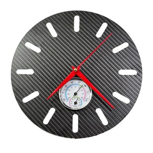 Puede incluir: Un reloj de fibra de carbono negro con manecillas rojas y un pequeño termómetro e higrómetro redondo en el centro.