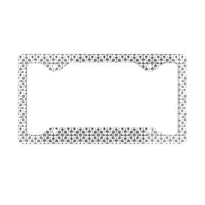 Puede incluir: Un marco rectangular para matrícula con un patrón geométrico repetitivo en blanco y negro. El diseño consiste en pequeños triángulos, cruces y puntos dispuestos en un motivo denso y simétrico por toda la superficie del marco.