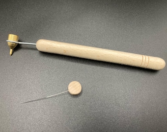 May include: A craft tool with a wooden handle and a brass tip, alongside a separate needle tool. The handle features three engraved lines. These tools are likely used for detailed craftwork.