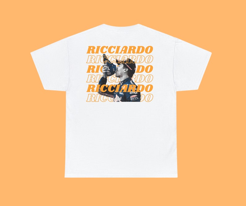 May include: White t-shirt with a repeated pattern of the word "RICCIARDO" in orange text. A photo of a race car driver is centered on the shirt.
