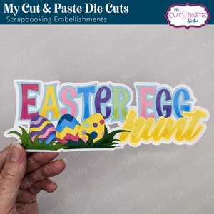 May include: A colorful die cut set for scrapbooking featuring the words "Easter Egg Hunt" with three decorated eggs in the grass.