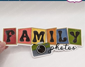 May include: A set of colorful die cuts spelling out "FAMILY" with a camera and the words "photos" in black script. The die cuts are designed for scrapbooking and crafting.