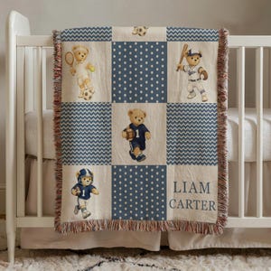 May include: A baby blanket with a patchwork design featuring teddy bears playing sports. The blanket has a cream background with blue polka dot and chevron patterns. The name "LIAM CARTER" is printed on the blanket.