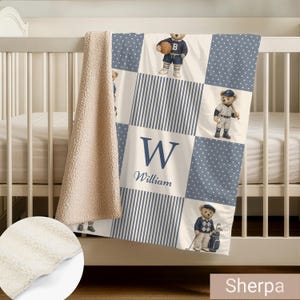 May include: A soft sherpa-backed blanket featuring a patchwork design with blue and white polka dots, blue and white stripes, and illustrations of teddy bears playing sports. The center square displays the letter W and the name William in blue.