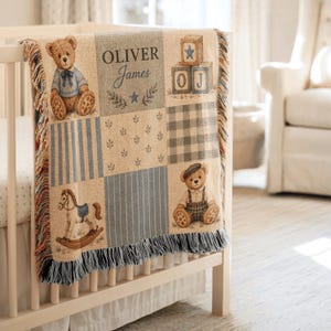 May include: A woven throw blanket featuring a patchwork design with illustrations of teddy bears, a rocking horse, and alphabet blocks. The blanket displays the name Oliver James in dark text, with blue and beige stripes, plaid, and leaf patterns.