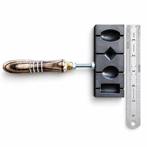 May include: A dark gray rectangular metal mold with four distinct geometric cavities, including oval, diamond, and rectangular shapes. A wooden handle with silver rings is attached via a threaded metal bolt. A 6-inch metal ruler is placed alongside.