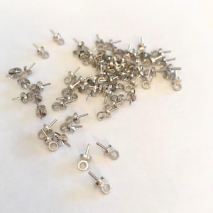 Pode incluir: Um monte de fechos de brincos prateados com um laço na parte superior e um poste na parte inferior.