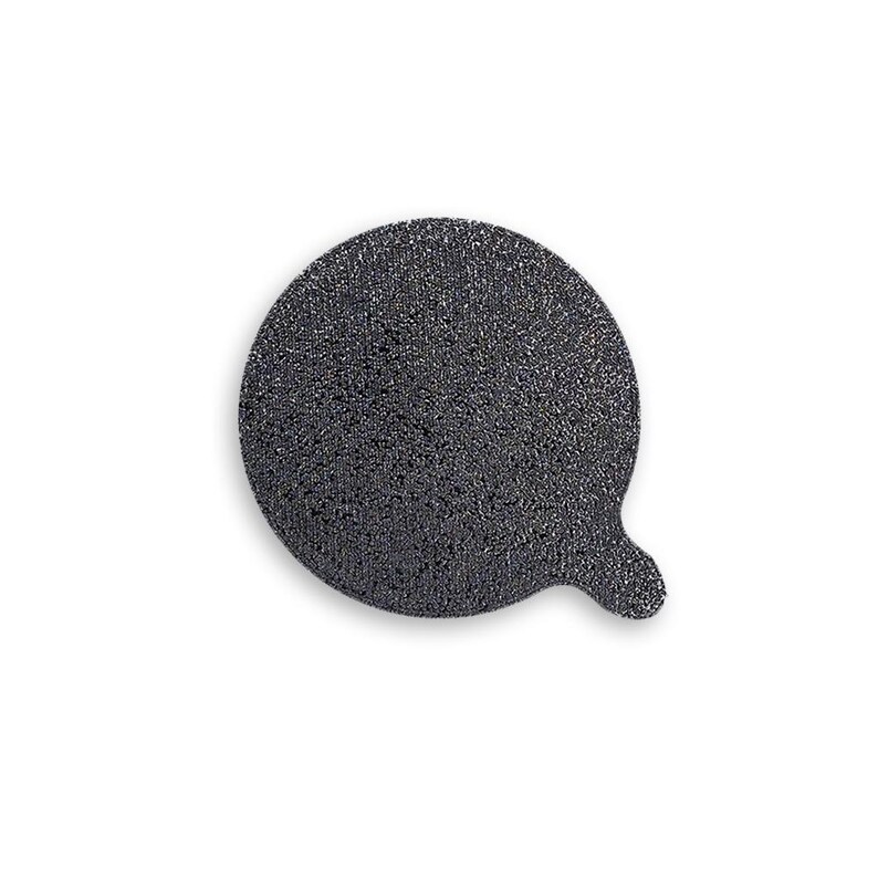 May include: A circular, dark gray, textured abrasive disc featuring a small, protruding tab on the lower right side. The surface has a coarse, granular appearance with a uniform dark charcoal color throughout the entire round shape.