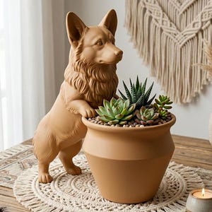 May include: A terracotta-colored dog statue leans on a matching planter filled with succulents and small pebbles. The dog has detailed fur and stands next to the pot. The planter sits on a round, cream-colored placemat.