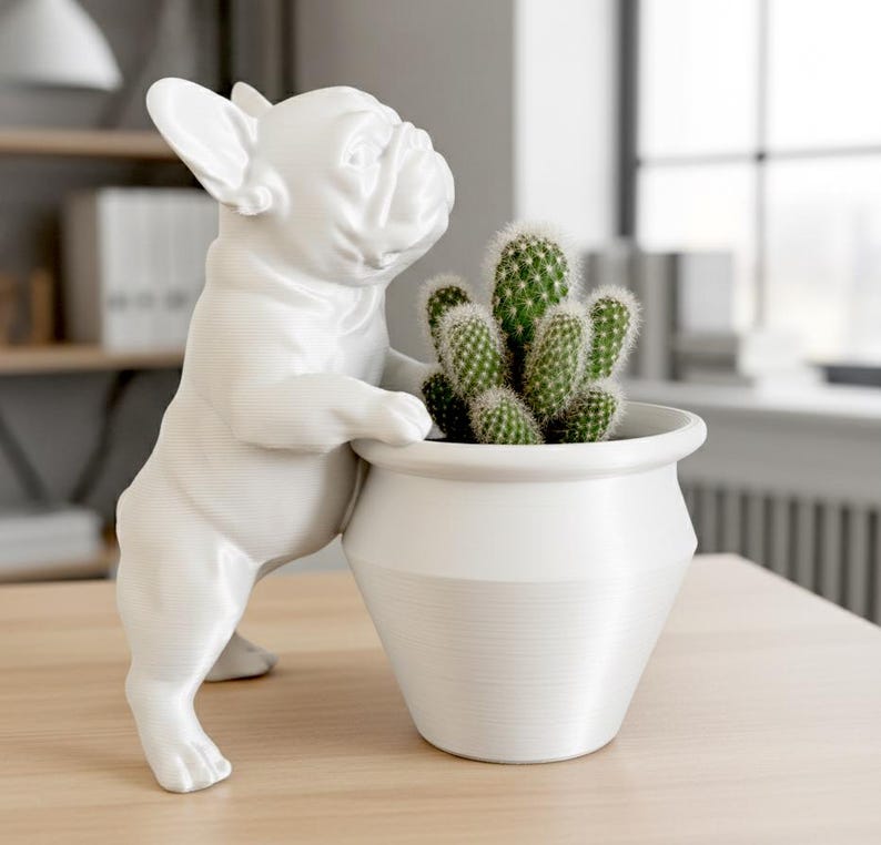 May include: A white French bulldog figurine standing on its hind legs with its front paws resting on the rim of a matching white planter. Inside the planter is a green cactus with multiple stems and small, sharp spines covering its surface.