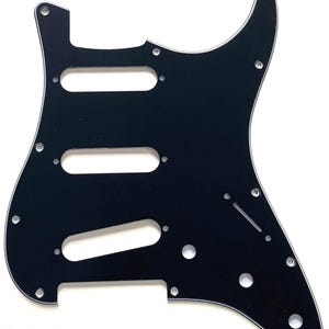 May include: A black guitar pickguard with three pickup cutouts and several screw holes. The pickguard has a white beveled edge and is designed for a Stratocaster-style guitar. The image is against a white background.