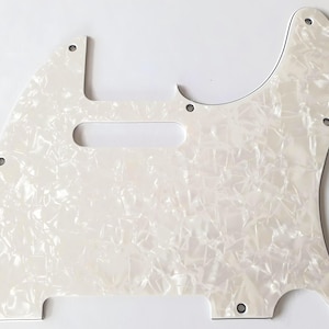 Könnte beinhalten: Ein perlweißes Gitarren-Schlagbrett mit einem wirbelnden, strukturierten Muster. Das Schlagbrett hat eine markante Form mit einem rechteckigen Abschnitt, einer gebogenen Kante und mehreren Schraubenlöchern zur Montage. Für E-Gitarren.