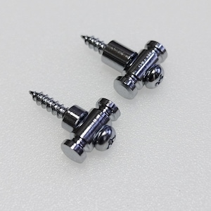 May include: Two chrome guitar string retainers. Each retainer has a screw, a cylindrical body, and a small, round head. The retainers are on a white surface. The retainers are likely for a guitar.