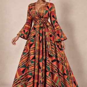 May include: A floor-length wrap dress featuring a vibrant geometric pattern in shades of orange, green, yellow, and black. The dress has a deep V-neckline, long flared bell sleeves, and a matching fabric tie belt at the waist with a full skirt.