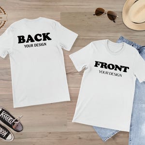May include: Two white short-sleeve t-shirts featuring black text. The left shirt displays the word BACK above the text YOUR DESIGN. The right shirt displays the word FRONT above the text YOUR DESIGN. The shirts are presented on a flat surface.