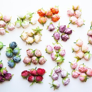 May include: Assortment of artificial flower buds in various colors, including pink, purple, blue, green, white, and orange. The buds are arranged in groups of five or six, with each group representing a different color.