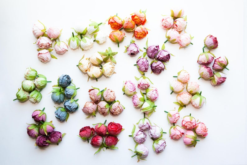 May include: Assortment of artificial flower buds in various colors, including pink, purple, blue, green, white, and orange. The buds are arranged in groups of five or six, with each group representing a different color.