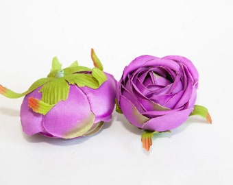 May include: Two purple silk artificial flower buds with green leaves. The flower buds are closed and have a ruffled texture.