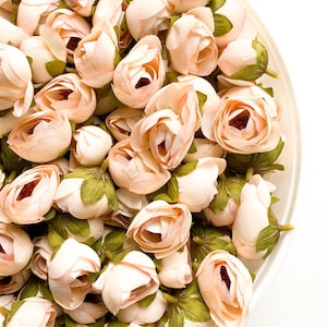 Puede incluir: Un bol lleno de una gran cantidad de pequeñas flores artificiales de color rosa pálido. Las flores tienen hojas verdes y están dispuestas en un patrón aleatorio.